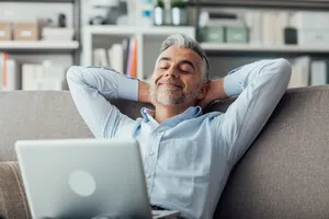 homem sentado no sofa sorrindo e olhando para o computador