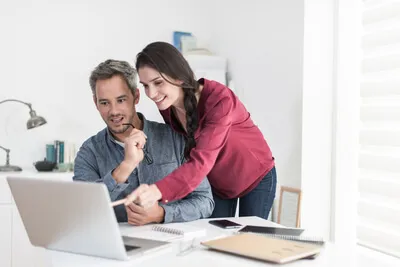 imagem de um casal sentado em frente a um computador, em um ambiente que parece ser um escritório