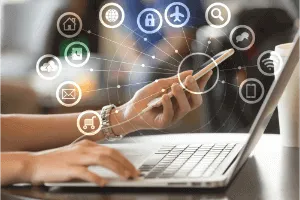 pessoa com computador e celular com aplicativos de atendimento